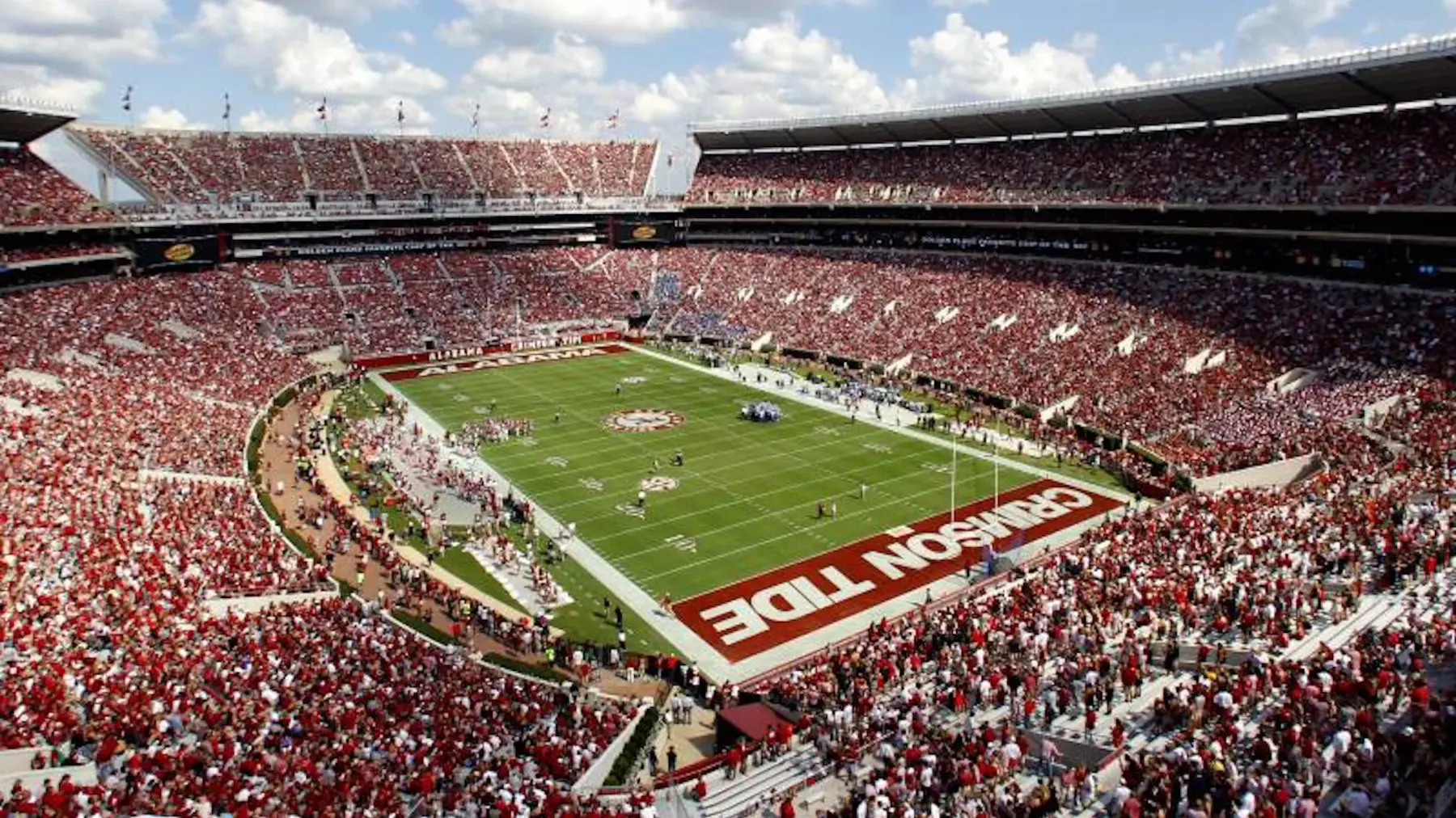 A full college football stadium seen from the upper deck on a sunny afternoon