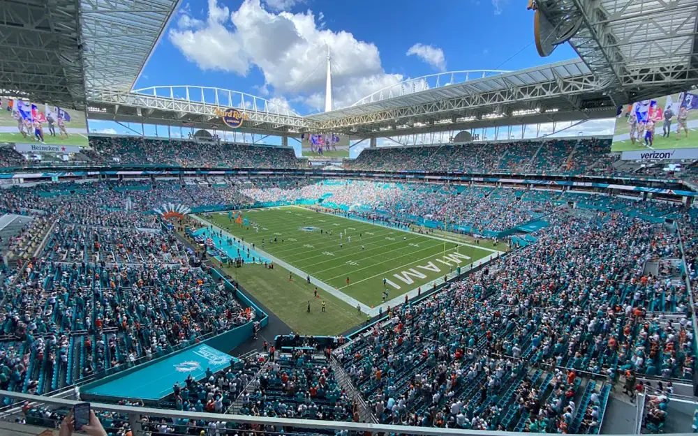 A football stadium under a canopy roof, viewed from high in the stands