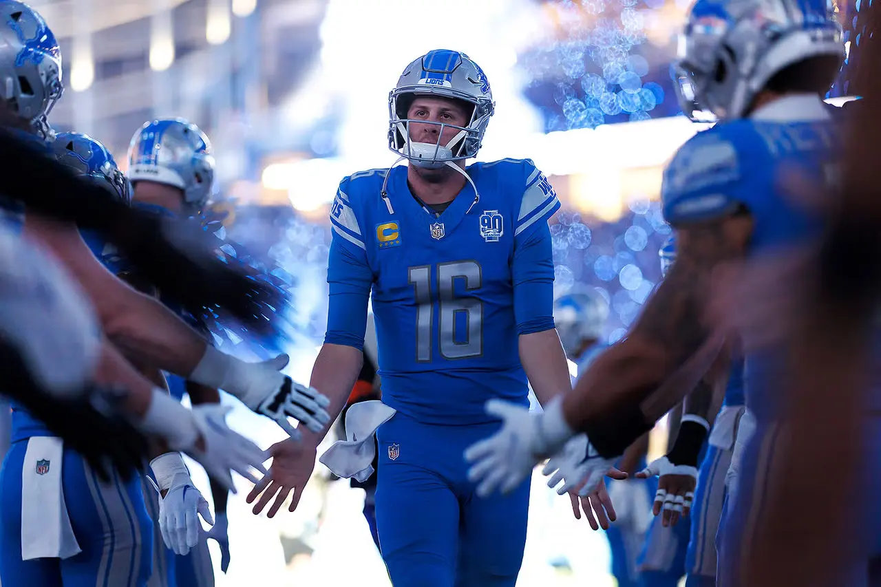 A football player walking out onto the field past a line of teammates